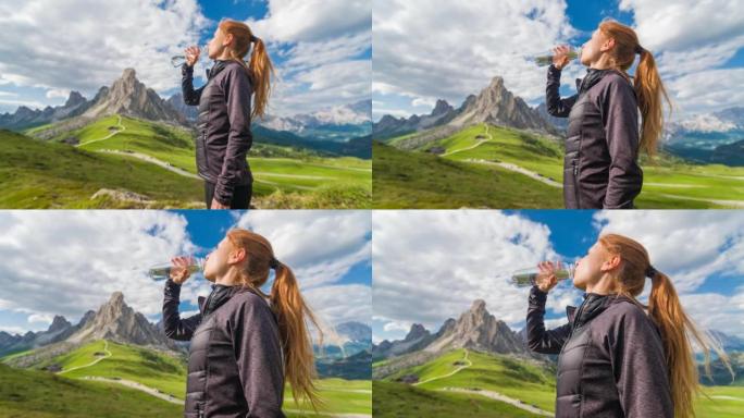 女人从可重复使用的水瓶中喝水，看着山脉