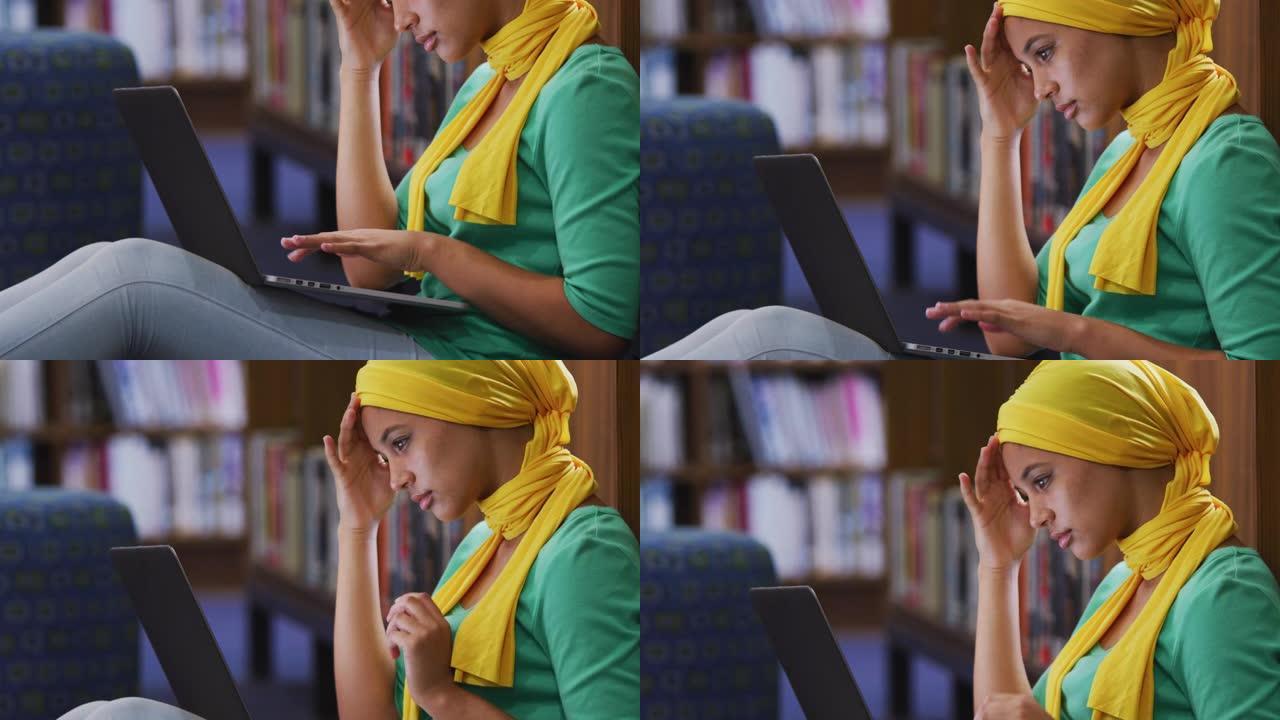 亚洲女学生戴黄色头巾坐著使用手提电脑