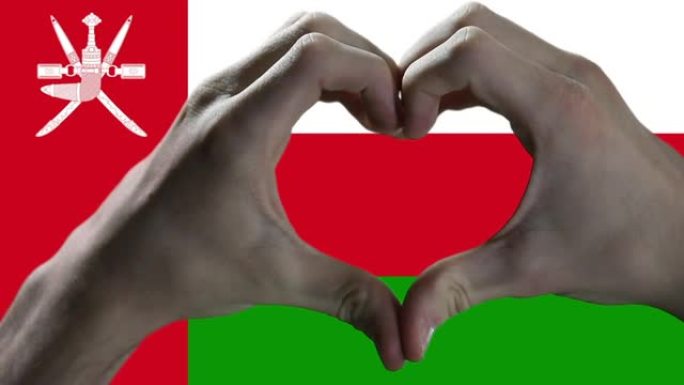 双手在阿曼国旗上显示心脏标志。