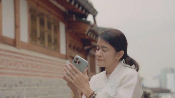 一名妇女拿着智能手机在韩国的旅游城市拍照。