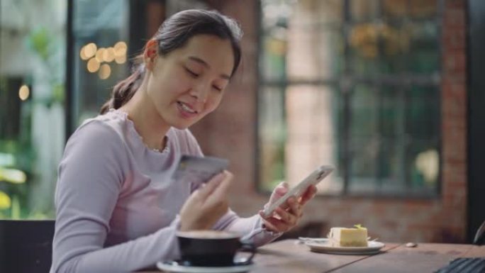 年轻的亚洲妇女用信用卡从手机上订购在线购物