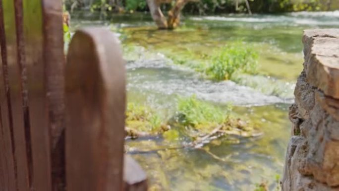 木门石墙，门打开，河与瀑布的山麓在墙后