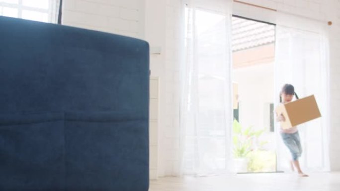 日本妈妈、爸爸和孩子微笑快乐地拿着纸板箱，移动物体走进家。