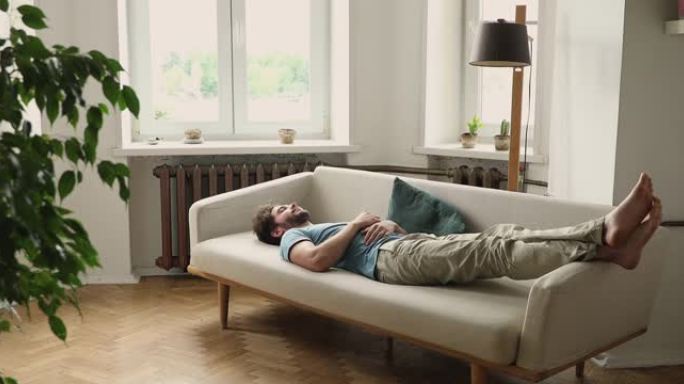 千禧一代的男人睡觉把腿放在沙发上