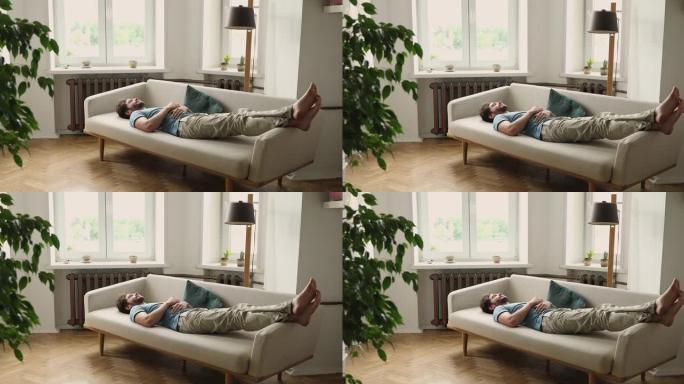 千禧一代的男人睡觉把腿放在沙发上
