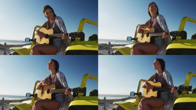 快乐的高加索女人坐在海边的沙滩车里弹吉他