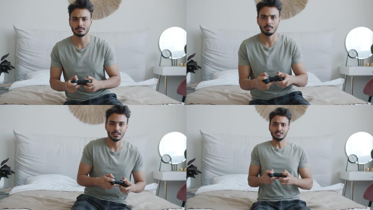 兴奋的阿拉伯男子喜欢独自玩电子游戏并看着相机的肖像