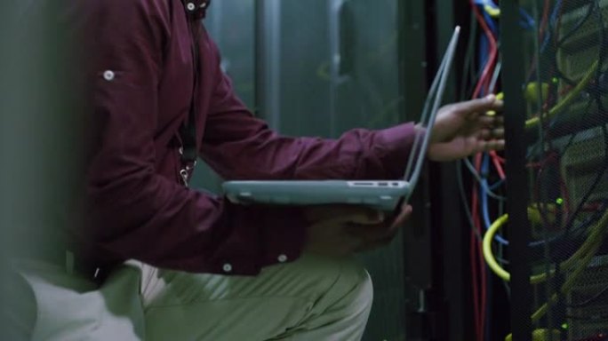 一名男子在服务器室工作时使用笔记本电脑的4k视频片段
