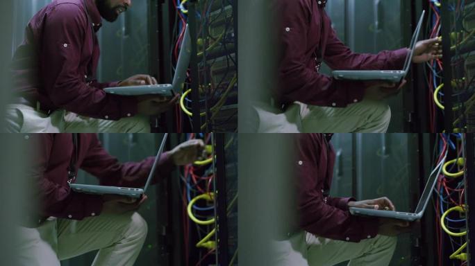 一名男子在服务器室工作时使用笔记本电脑的4k视频片段