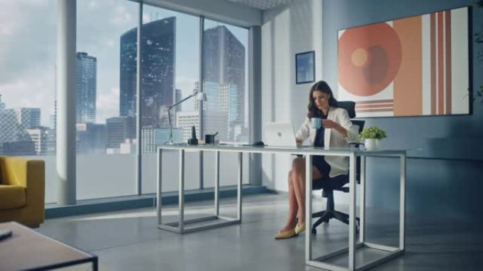 年轻成功的白人女商人坐在办公桌前在大城市办公室的笔记本电脑上工作的肖像。自信的公司首席执行官计划电子