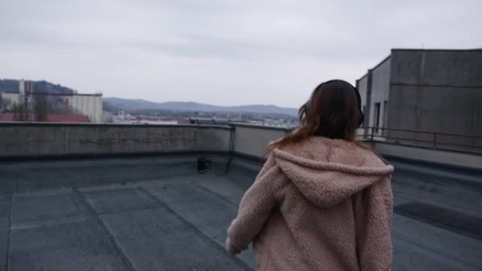 女人在屋顶上散步时听音乐，欣赏城市景观