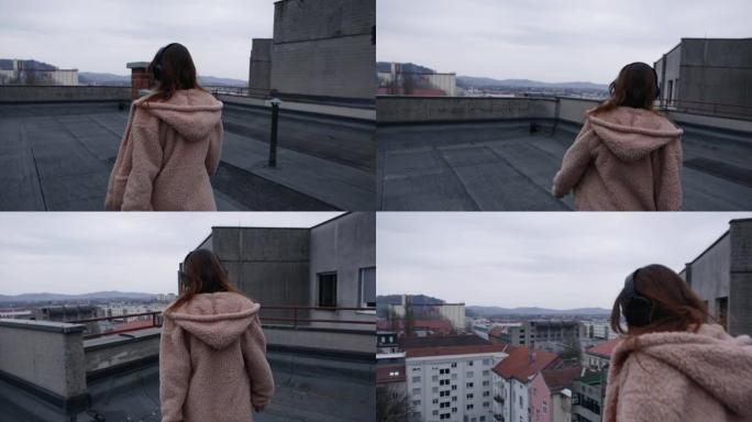 女人在屋顶上散步时听音乐，欣赏城市景观