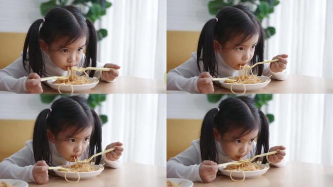 年轻的亚洲女孩喜欢吃意大利面，一个小女孩的肖像吃意大利面配沙拉、西红柿、西兰花和红酱