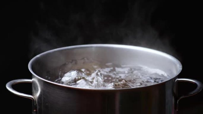 黑色背景上的一锅开水。沸腾的水泡。慢动作镜头