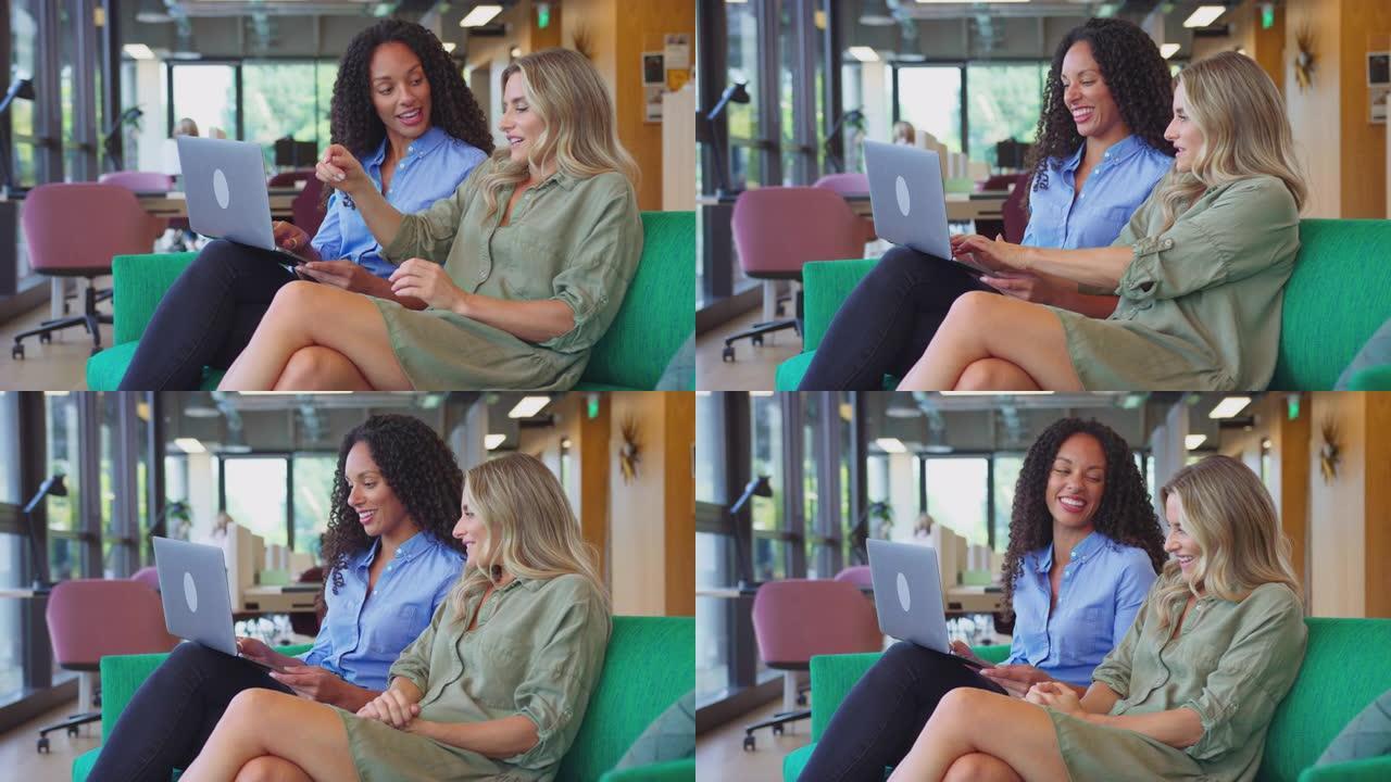 两名手提电脑平板电脑的女商人在现代办公室的休息座位区举行非正式会议-慢动作拍摄