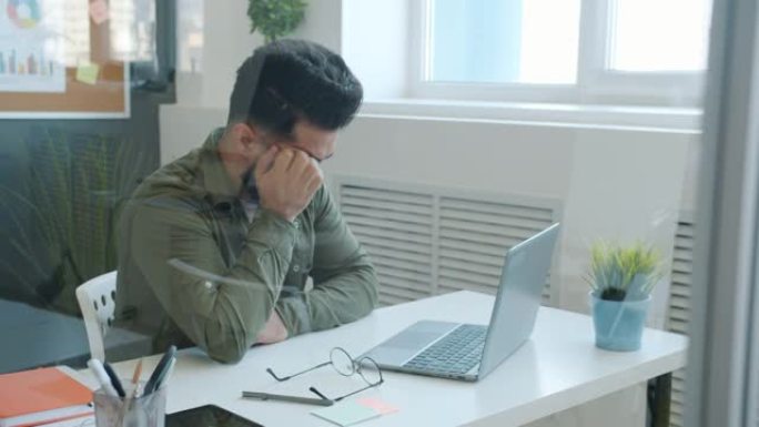 疲惫的中东商人使用计算机和触摸头部感到压力和疲惫