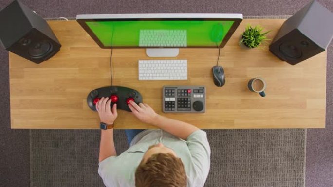 在创意办公室绿屏计算机上工作的男性视频编辑器的俯视图-慢动作拍摄