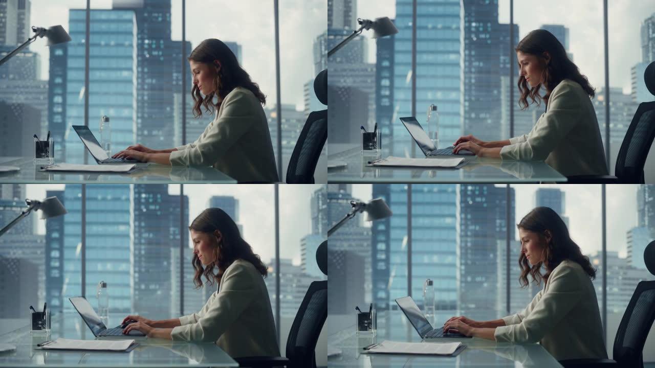 年轻成功的女商人坐在办公桌前在城市办公室的笔记本电脑上工作的肖像。有才华的顶级经理做数据分析，电子商