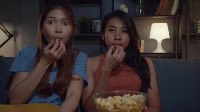 迷人的亚洲情侣休闲享受快乐时刻焦点观看在线电影娱乐晚上在家沙发客厅吃爆米花网站。生活方式活动检疫概念