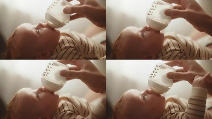 真实的特写镜头，一个新生儿躺在婴儿床的背上，从小婴儿奶瓶里喝牛奶。白人新生儿在家中的肖像。童年和父母