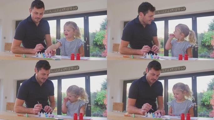 父亲和年幼的女儿一起在家里的桌子上做工艺和绘画装饰很开心