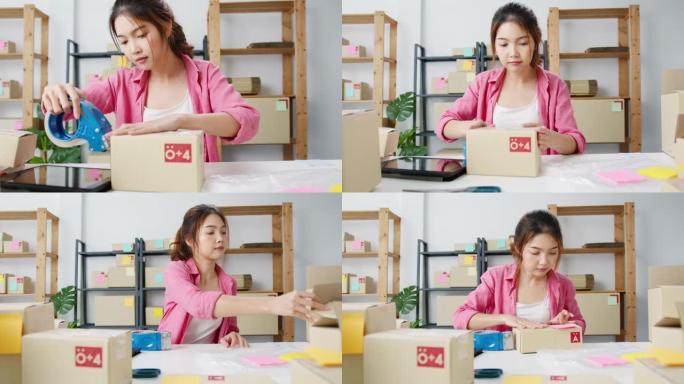 年轻的亚洲企业家商人包装产品在纸箱中交付给客户，在家庭办公室工作。