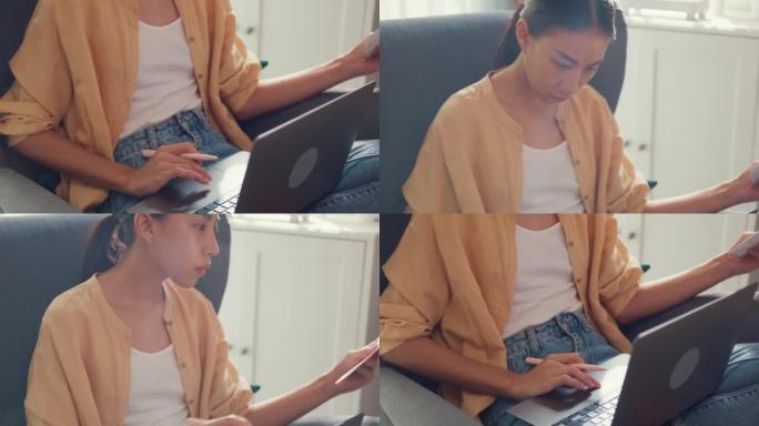 特写的年轻亚洲女孩或大学生坐在沙发椅上，用电脑笔记本电脑打字并检查文书工作中的数据图表在家里的客厅报