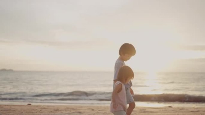 亚洲男孩和小女孩在海滩上散步。
