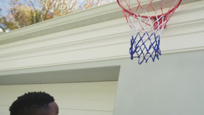 非裔美国爸爸背着儿子在篮球圈扣篮