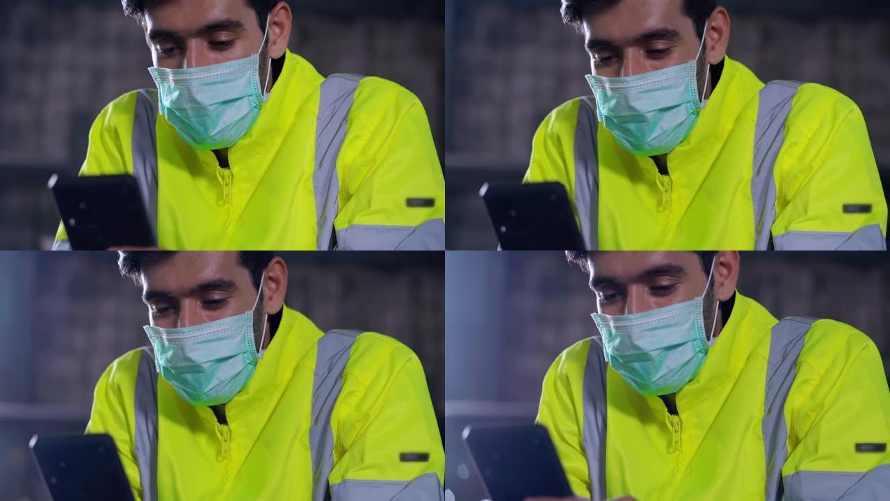 中东种族的年轻人戴着防护口罩，试图通过智能手机找到工作，而工厂由于冠状病毒或Covid-19.Une