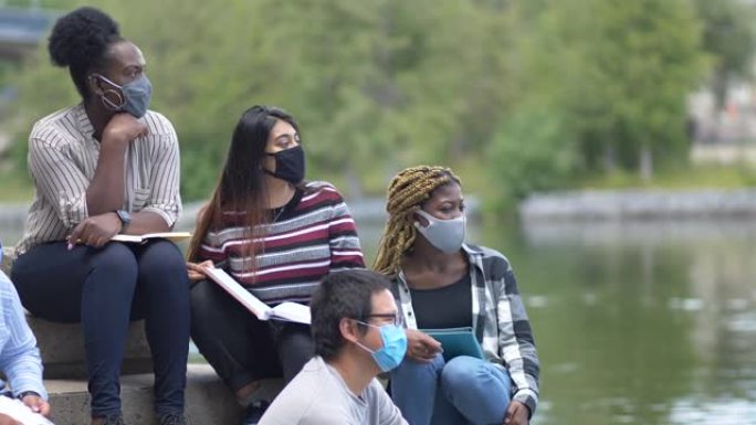 多民族学生戴口罩坐在校园