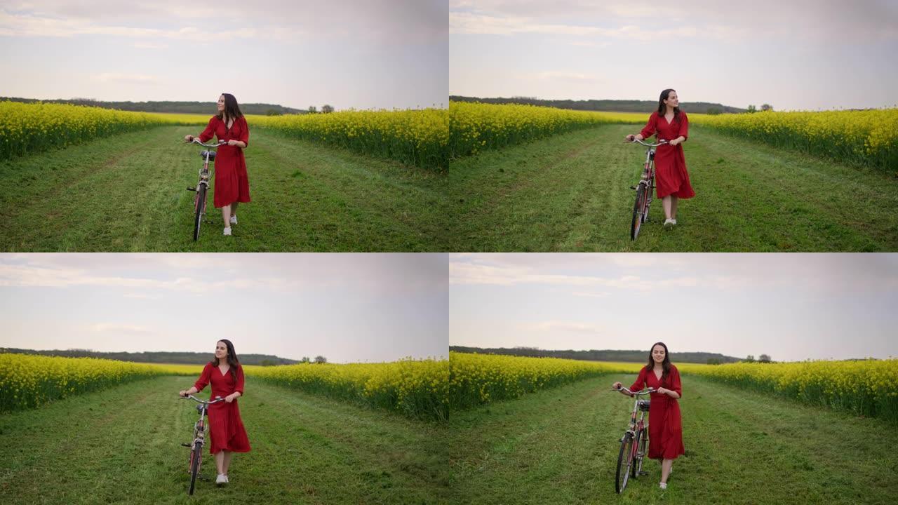 慢动作，追踪一个穿着红色连衣裙的黑发女郎的镜头，她骑着自行车穿过一片充满黄色金鱼草的草地