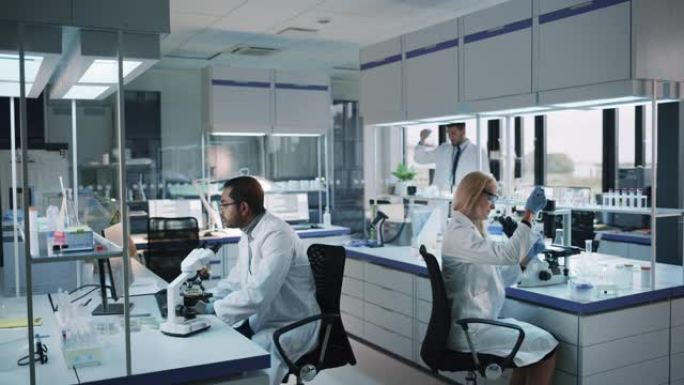 医学研究科学家团队致力于新一代疾病治疗。他们使用显微镜，试管，微量移液器并写下分析结果。实验室看起来
