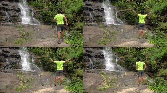 在雨林中进行越野跑的过程中，在瀑布上休息的男性越野跑运动员