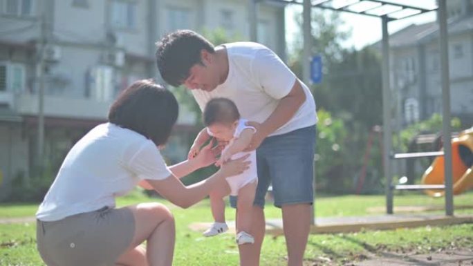 亚洲华裔家长教男婴学第一步清晨在公园散步