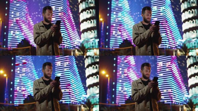 一名手持电话的男子在网上的黑暗城市街头购物。人们在霓虹灯的夜晚散步，并在未来照明建筑附近使用智能手机