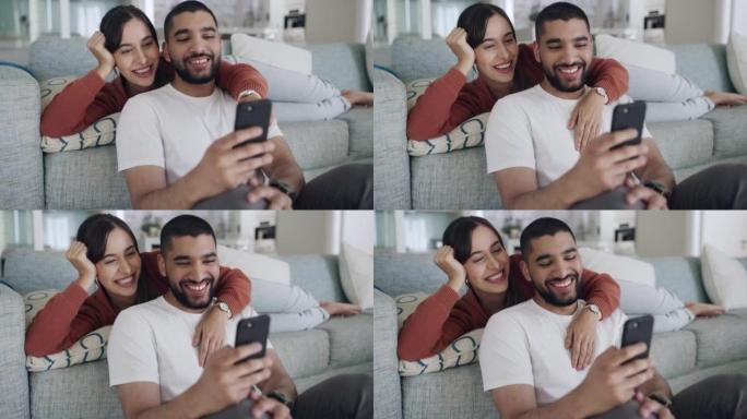 幸福而深情的夫妻使用电话发短信，在线聊天或浏览社交媒体。恋爱中的男朋友和女朋友一起在沙发上笑着放松。