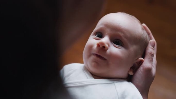 一个可爱的棕色眼睛的快乐新生婴儿的真实特写镜头对他的妈妈微笑