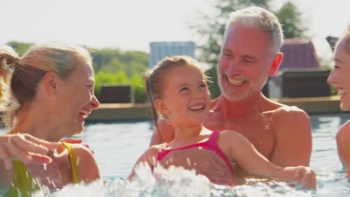 暑假微笑的多代家庭在游泳池里嬉戏