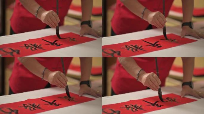 亚洲中国男性的手为即将到来的农历新年庆祝活动而练习中国书法，目的是通过将其写在红色纸上来实现繁荣和良