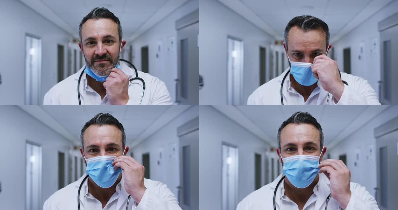 微笑的白人男性医生在医院走廊上戴上口罩的肖像