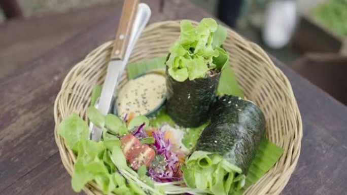 在柳条篮子里供应素食自制海藻卷的女人