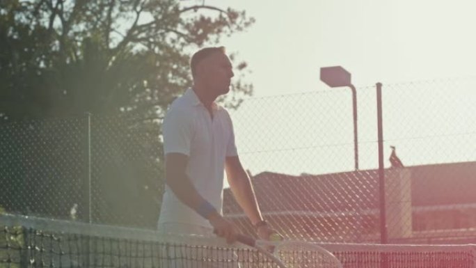 成熟的网球运动员拿着球和他的网球拍