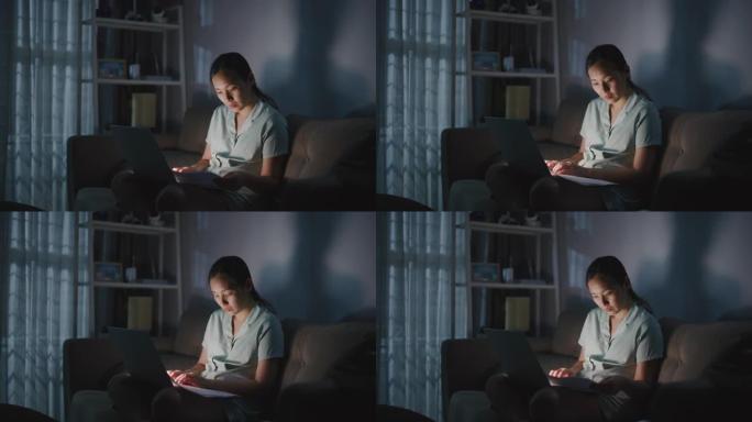 亚洲妇女晚上在家工作和使用笔记本电脑