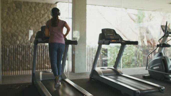 亚洲运动女子在健身房的跑步机上锻炼