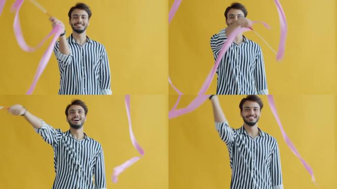 顽皮的阿拉伯男子跳舞，挥舞着黄色背景上的艺术体操丝带