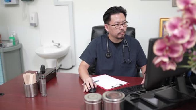 亚洲中国中年男性医生在台式电脑上查看患者记录