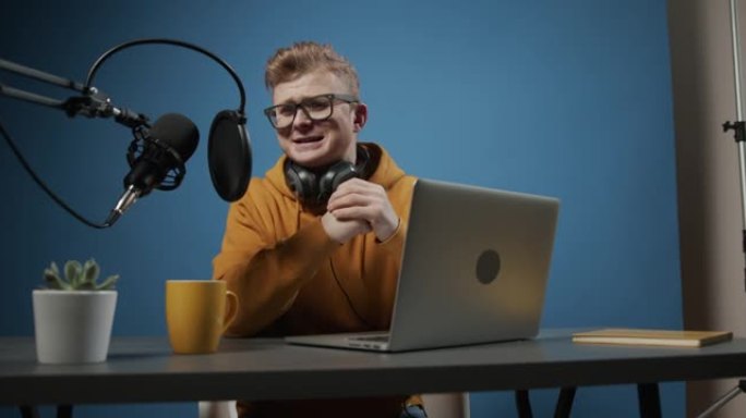 录制结束后，一位年轻的电台dj正在用笔记本电脑在录音棚里喝茶并与他的朋友聊天。