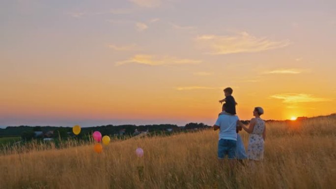 四口之家在太阳落山时在草地上玩气球的慢动作拍摄