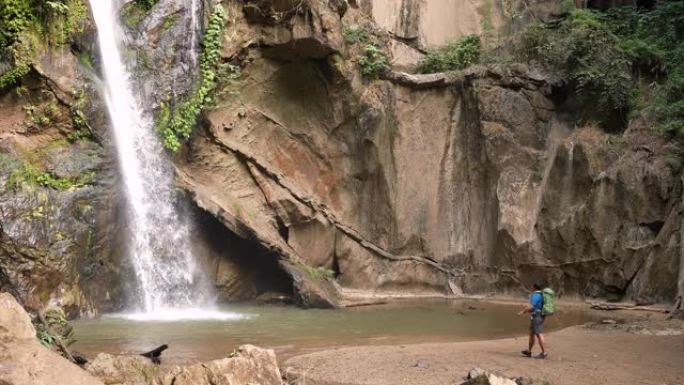 雄性徒步旅行者在雨林中徒步旅行在绿色森林中的小溪瀑布探险